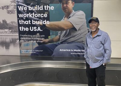 Simeon Fowler at the airport with a SourceAmerica Sign hanging on the wall behind him.