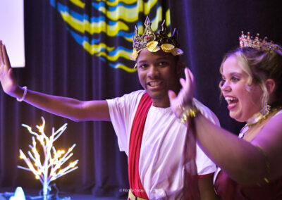 Two High school students in Greek mythology costumes wave to audience members after they took part in performing "The Stories of the Stars".