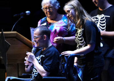 Lee Sorenson, BAC Arts Program Manger on stage with Emcees at the podium on the King Center stage.