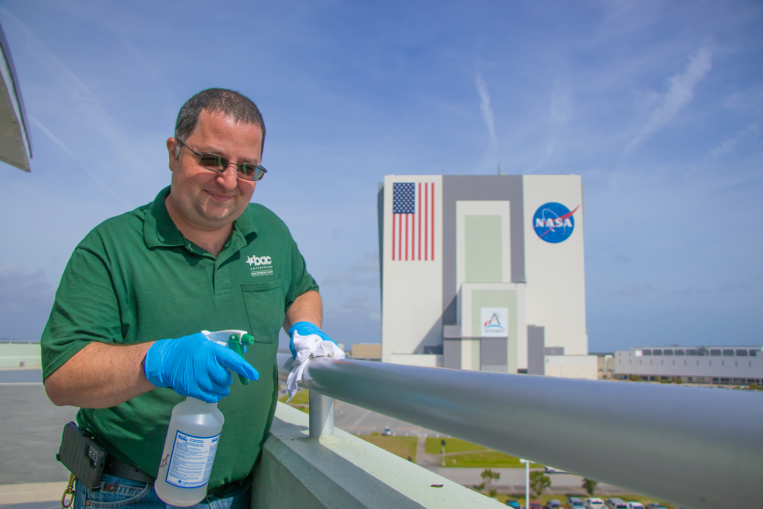 BAC_KSC_Custodial_JeremyHebert_23March2022_022 SMALL BAC Employee Cleaning hand railing in front of NASAs VAB building