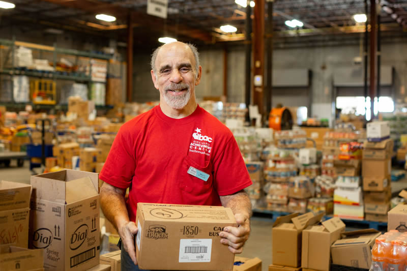 Male employee sorting boxes in a grocery store warehouse