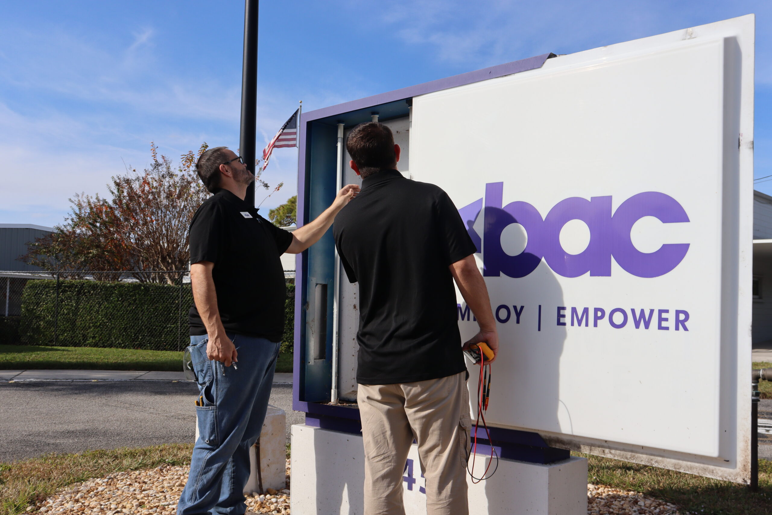 Facility workers at BAC inspecting a sign for damage