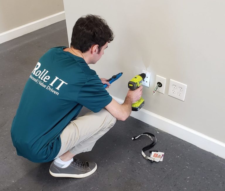 Nick a young man working in an Information Technology position checking cables at a wall plate