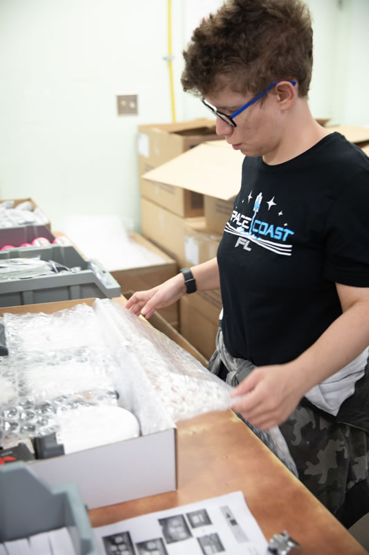 Female employee packing a box of assembled product inside manufacturing facility
