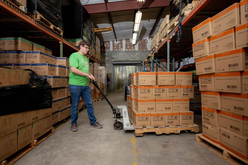 Male employee using a pallet jack in a warehouse