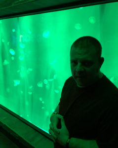 Justin admires the green water in the jellyfish tank.